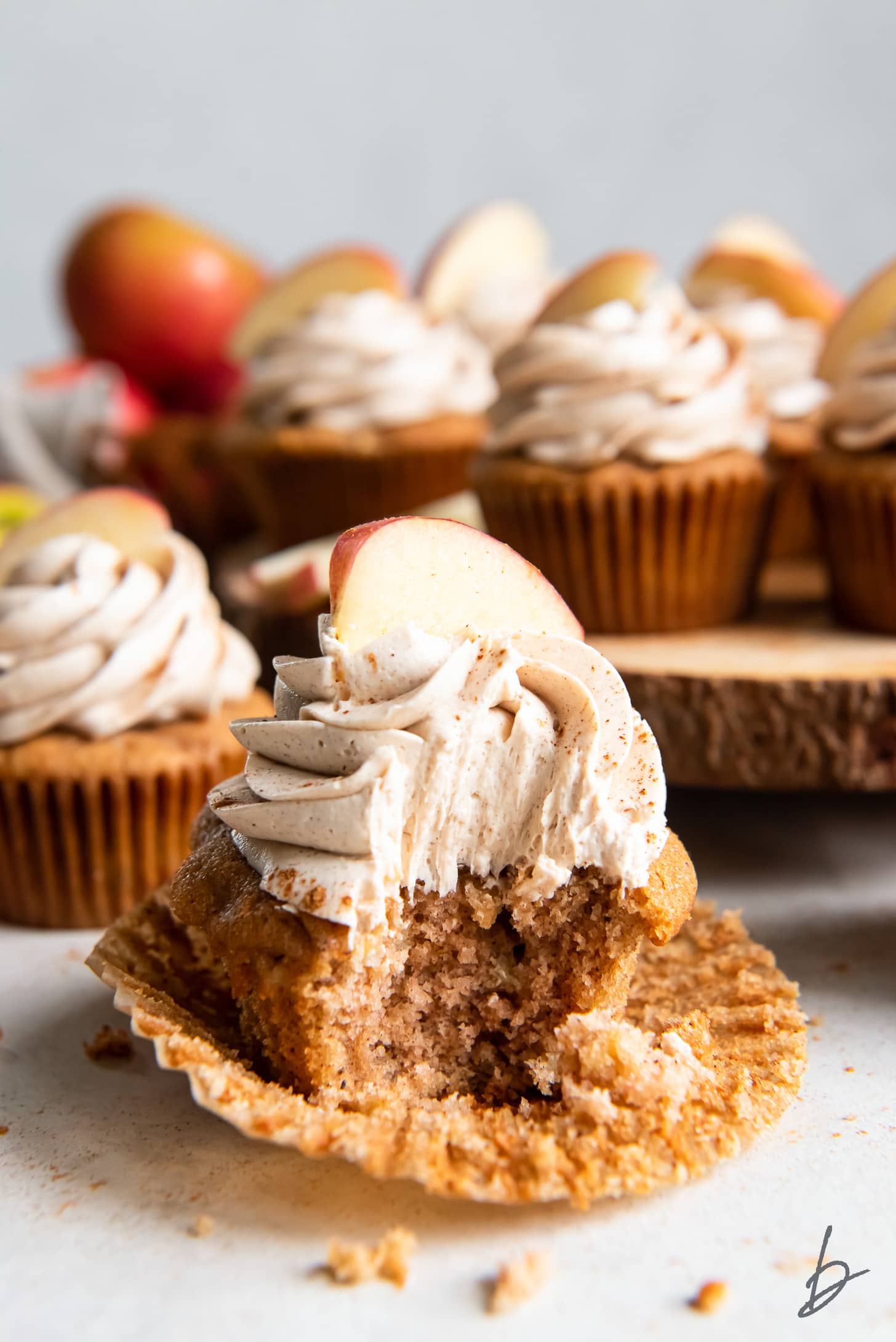 apple spice cupcake with a bite sitting on open paper cupcake liner.