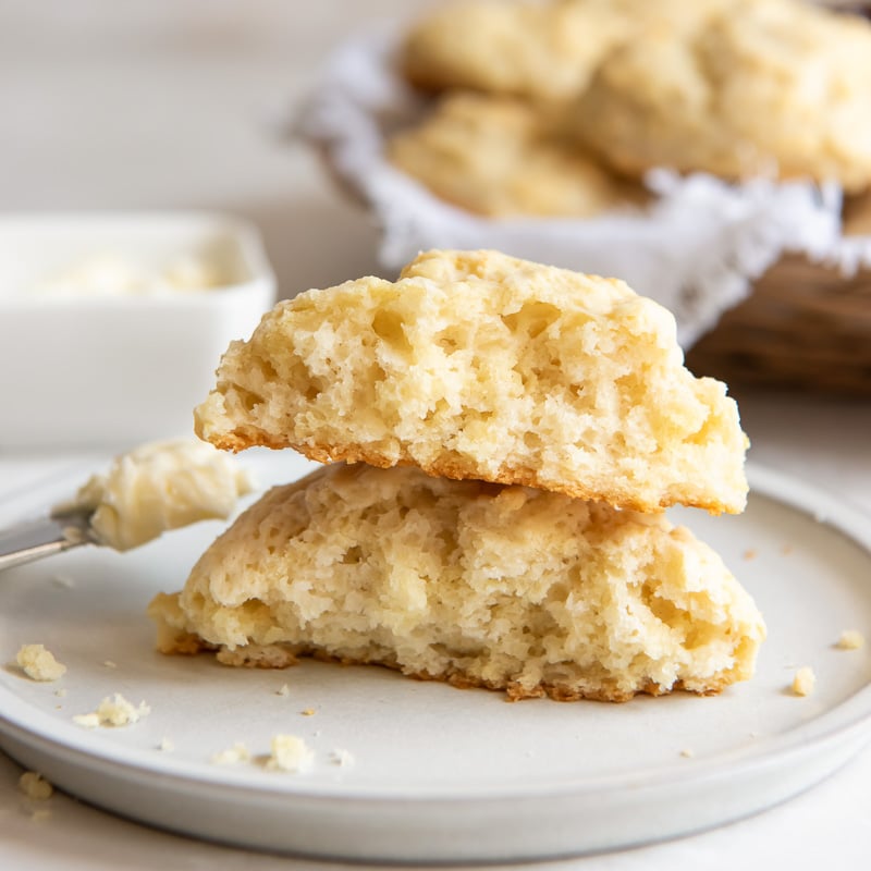 two halves of a buttermilk drop biscuit stacked on top of each other on plate.