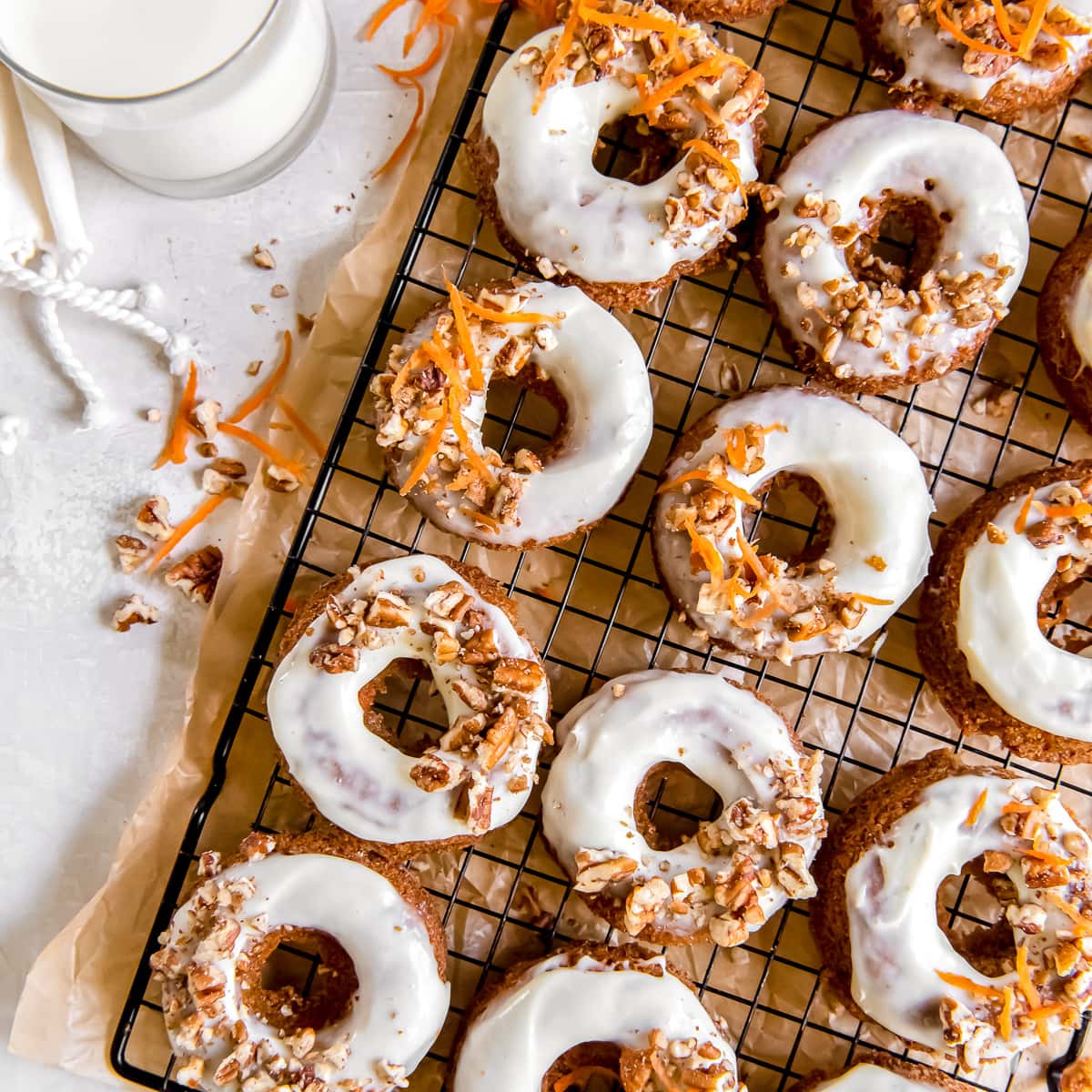 carrot cake donuts with cream cheese glaze and shredded carrot on wire rack.