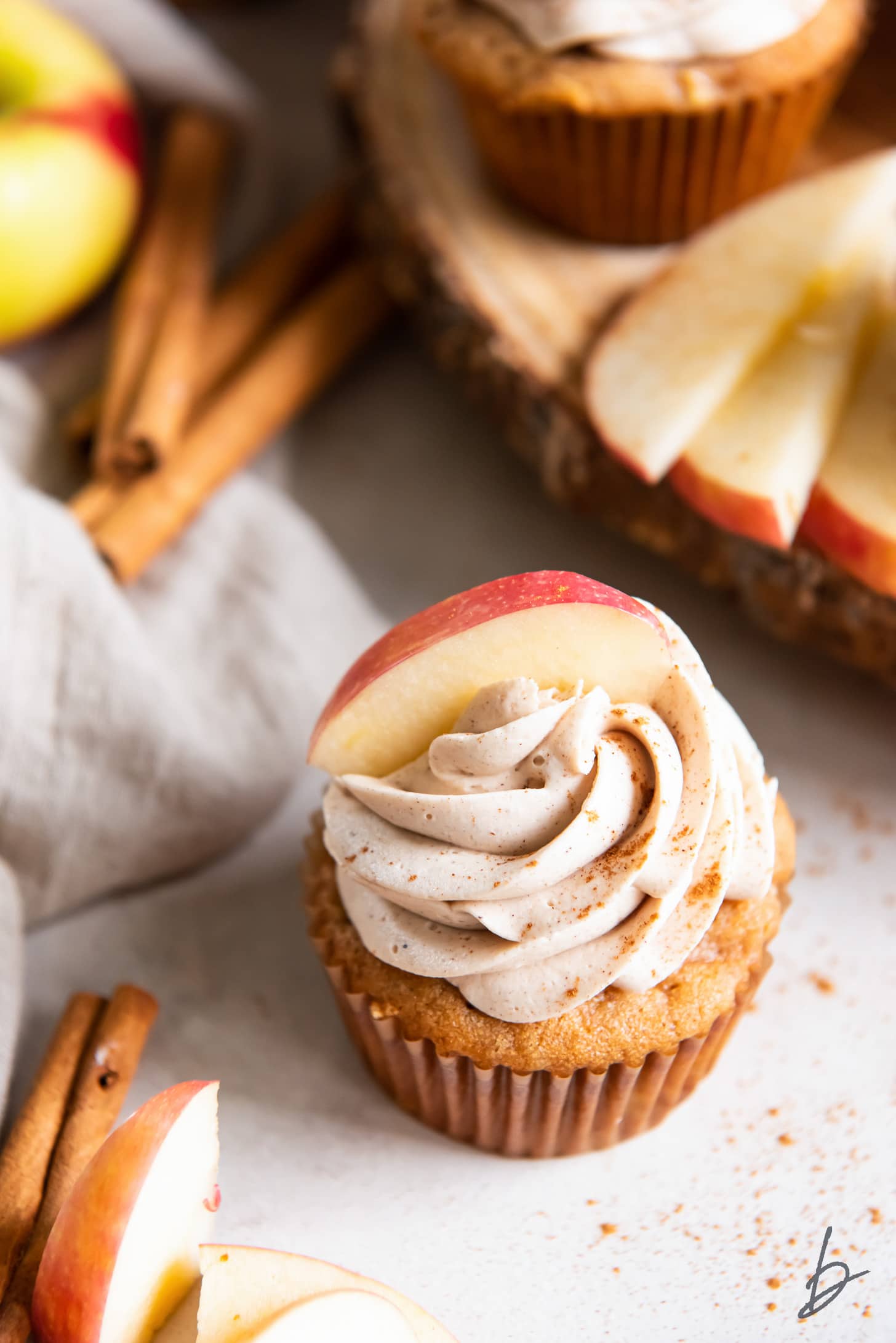 apple spice cupcake with cinnamon buttercream frosting and apple slice on top.