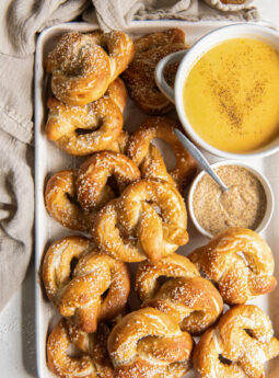 soft pretzels on baking sheet with bowl of beer cheese dip and bowl of mustard.