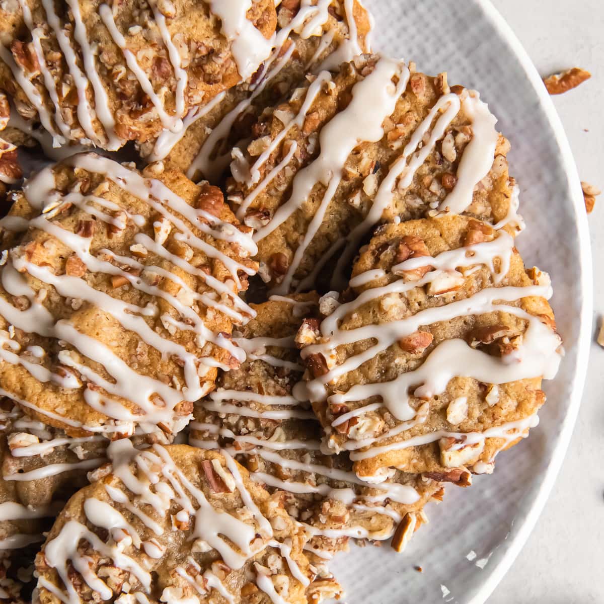 plate of maple brown sugar cookies with pecans and icing drizzle.