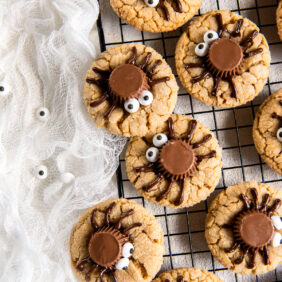 peanut butter spider cookies on cooling rack next to white cloth.