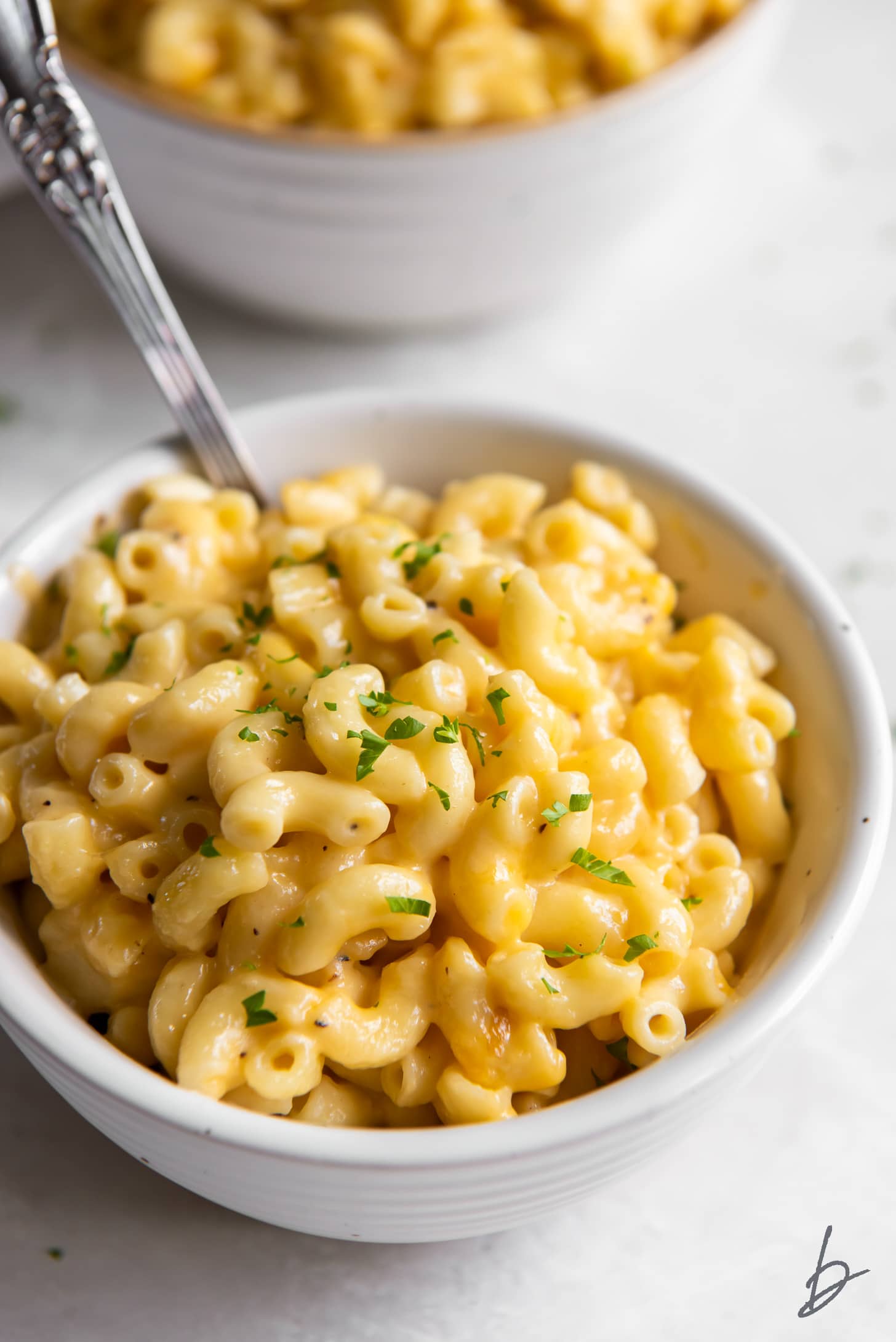 creamy mac and cheese in a white bowl with a spoon.