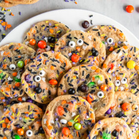 halloween cookies with sprinkles, m&ms and candy eyes on a plate.