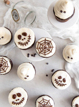tops of chocolate cupcakes with vanilla frosting decorated as skeletons, spider webs and ghosts.