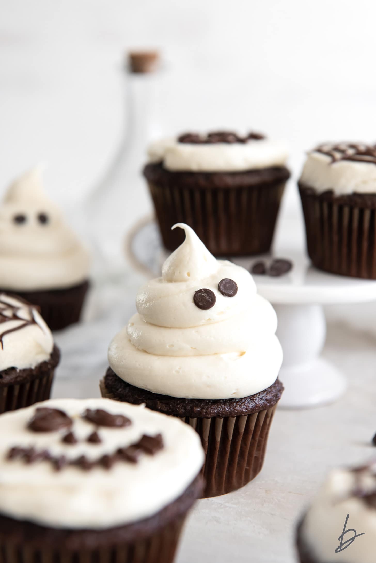 halloween cupcake decorated like a ghost with vanilla frosting and chocolate chip eyes.