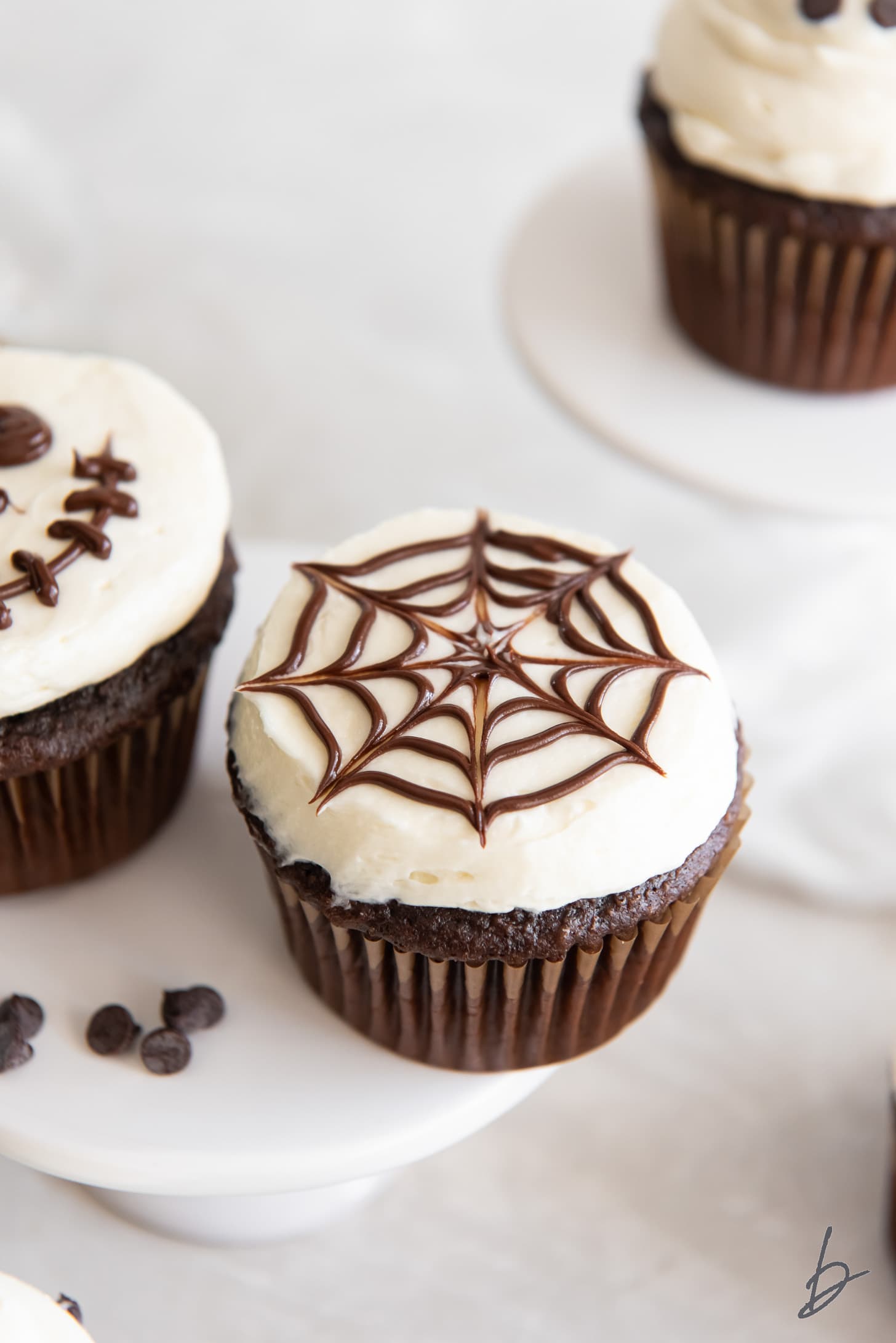 spiderweb cupcake with vanilla frosting and melted chocolate design on top.