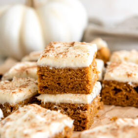 stack of two pumpkin bars topped with cream cheese frosting.