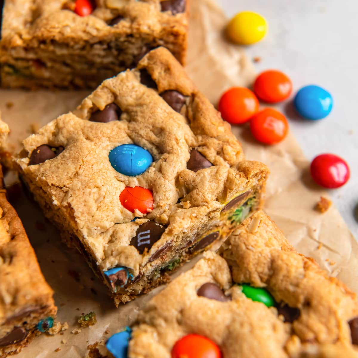 cookie bar with m&ms and chocolate chips on parchment paper next to another bar..
