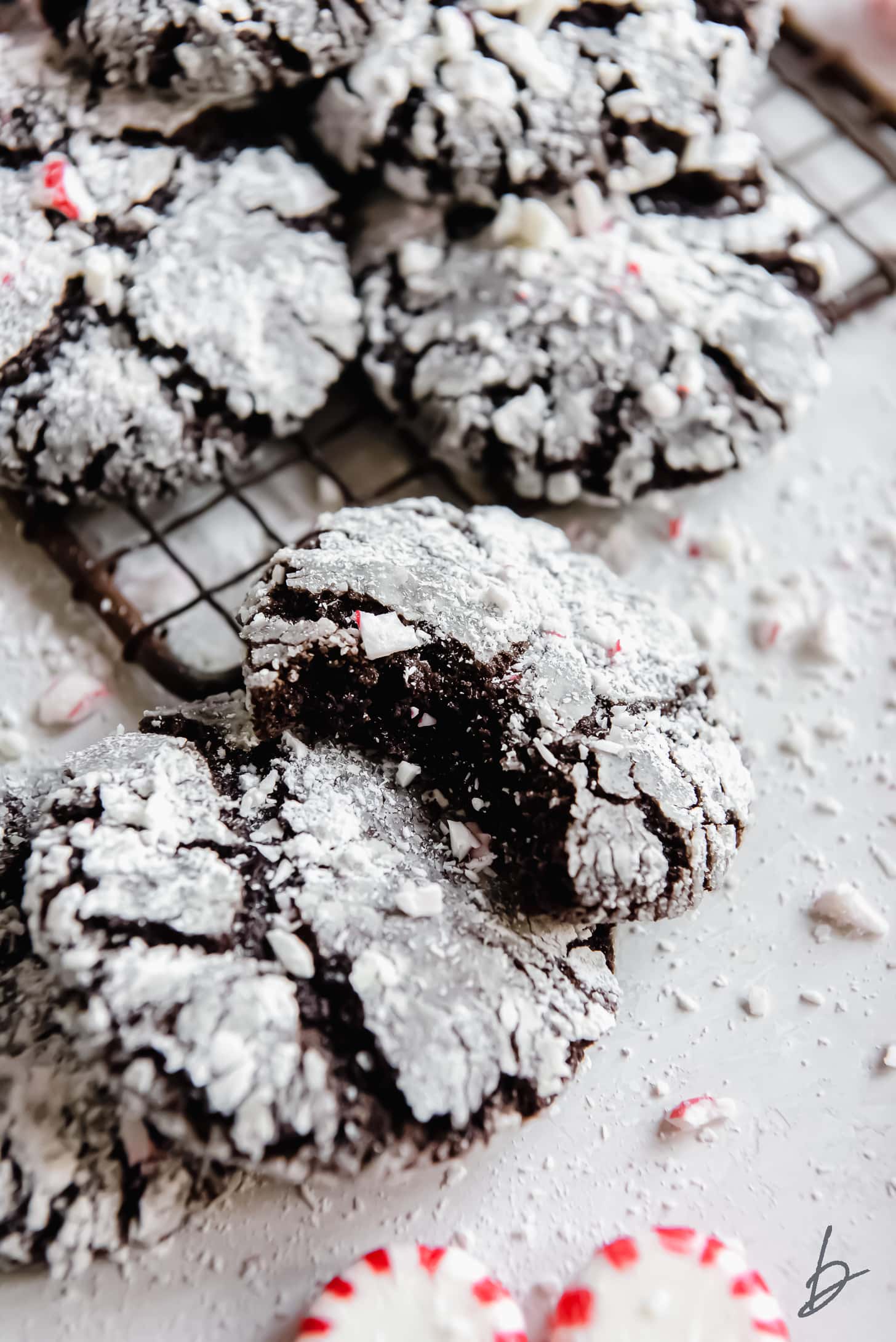 chocolate peppermint crinkle cookie with a bite leaning on top of another cookie.