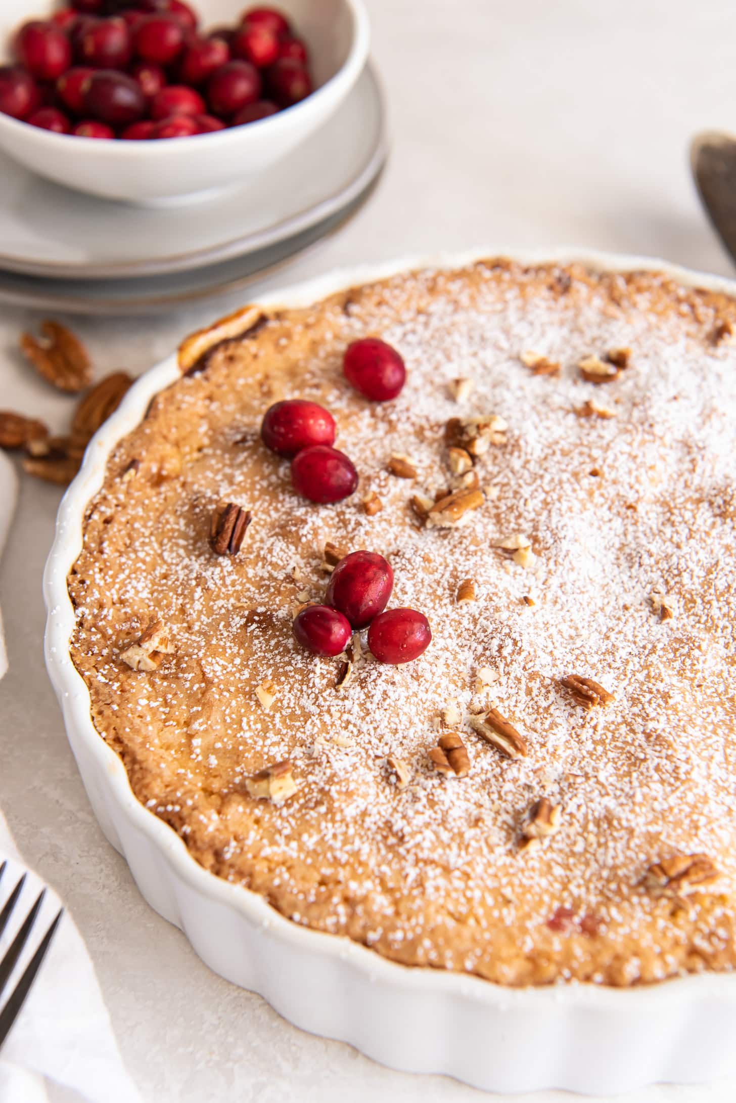nantucket pie with dusting of confectioners' sugar and a couple fresh cranberries on top.