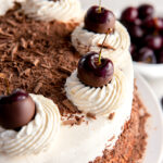 top of black forest cake with whipped cream, cherries and chocolate shavings.