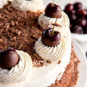 top of black forest cake with whipped cream, cherries and chocolate shavings.