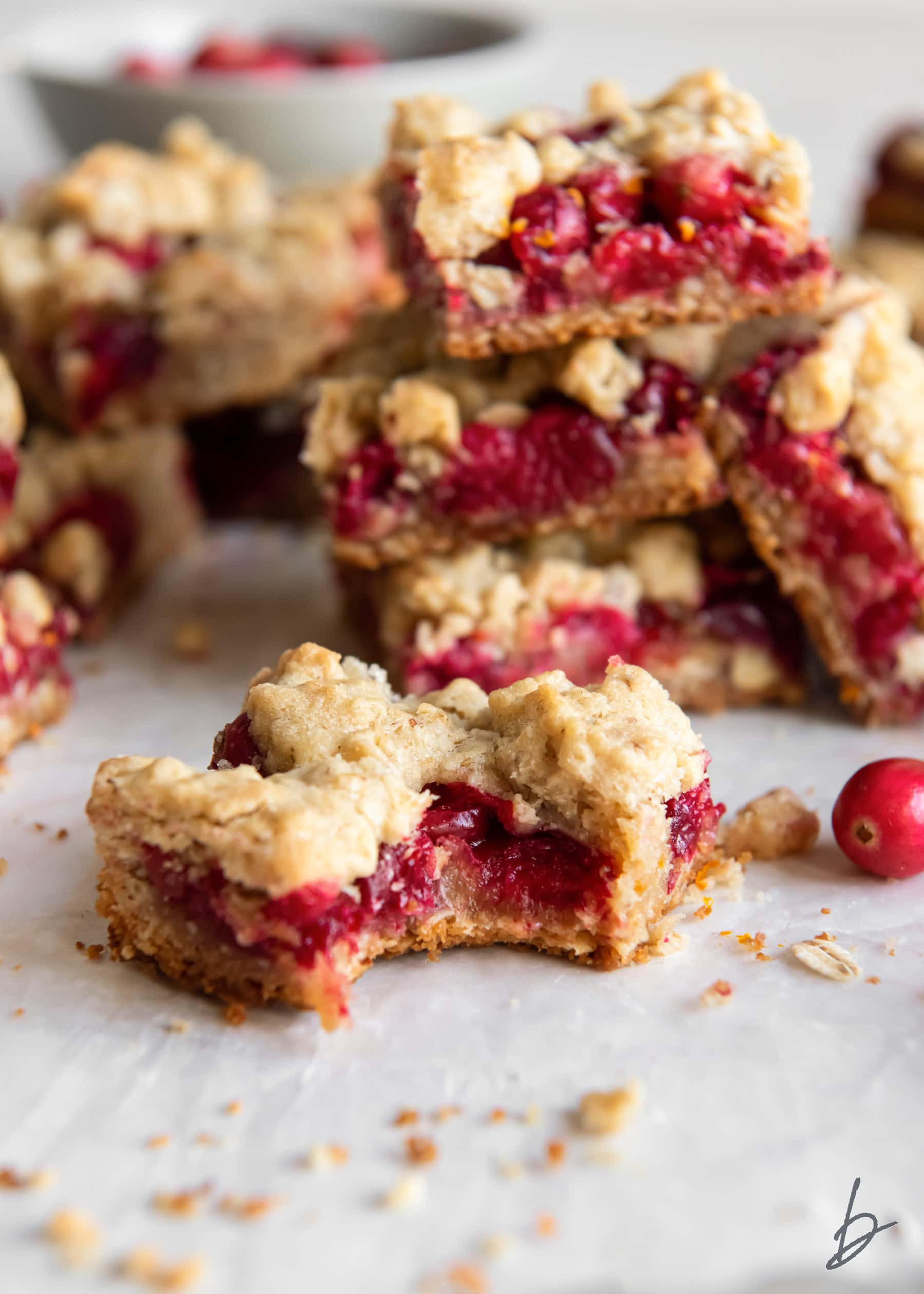 cranberry crumb bar with a bite in front of stack of more bars.