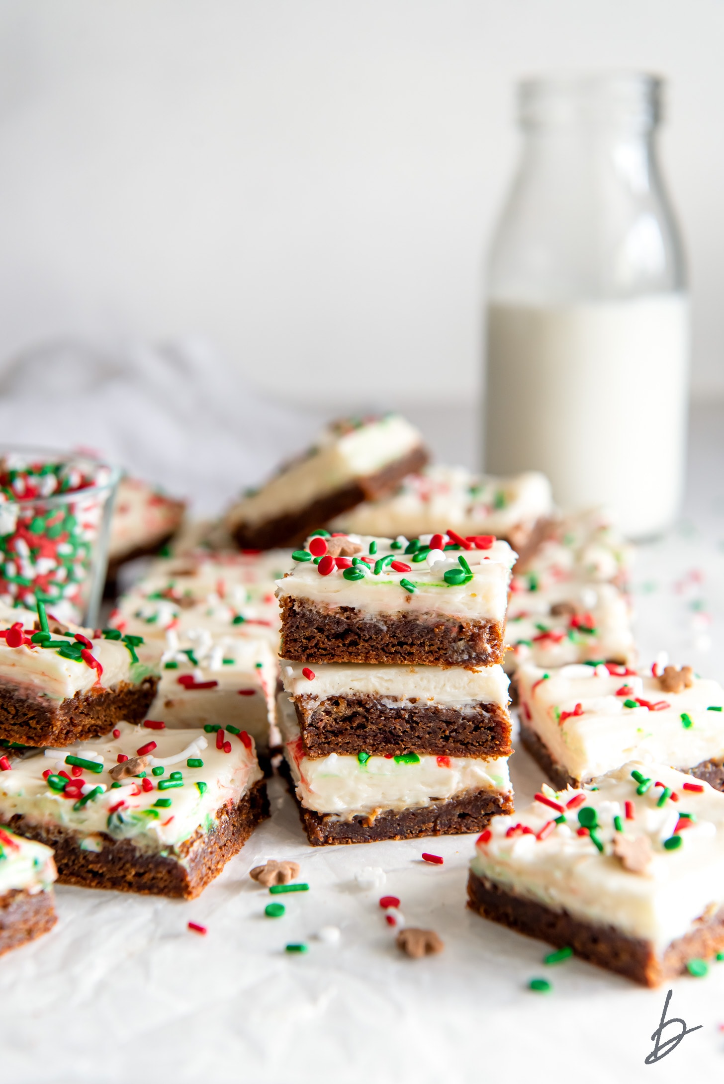 stack of gingerbread cookie bars surrounded by more bars and a glass bottle of milk.