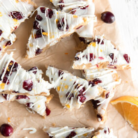 cranberry bliss bars with dried cranberries and white chocolate drizzle on parchment paper.