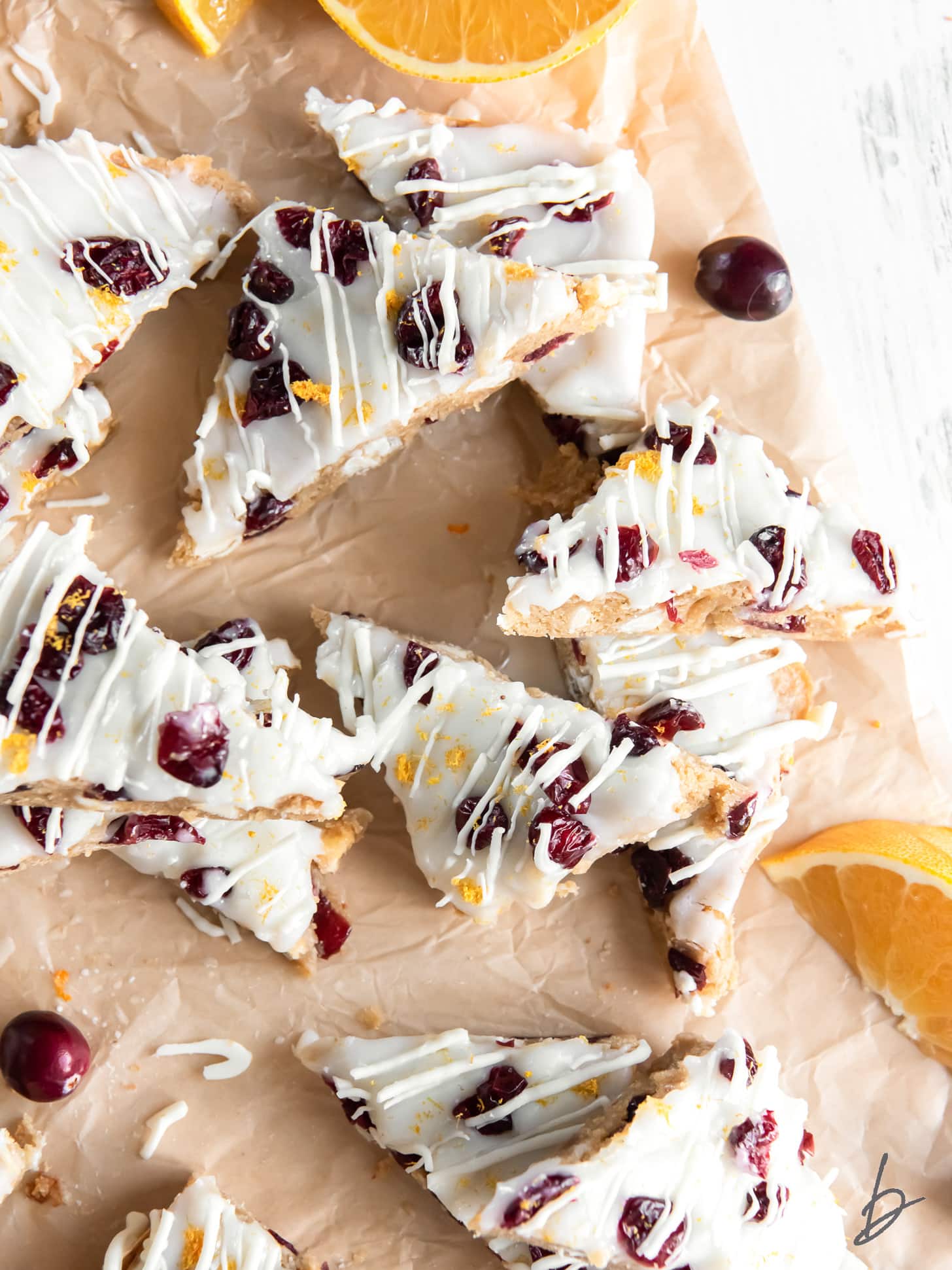 cranberry bliss bars with dried cranberries and white chocolate drizzle on parchment paper.