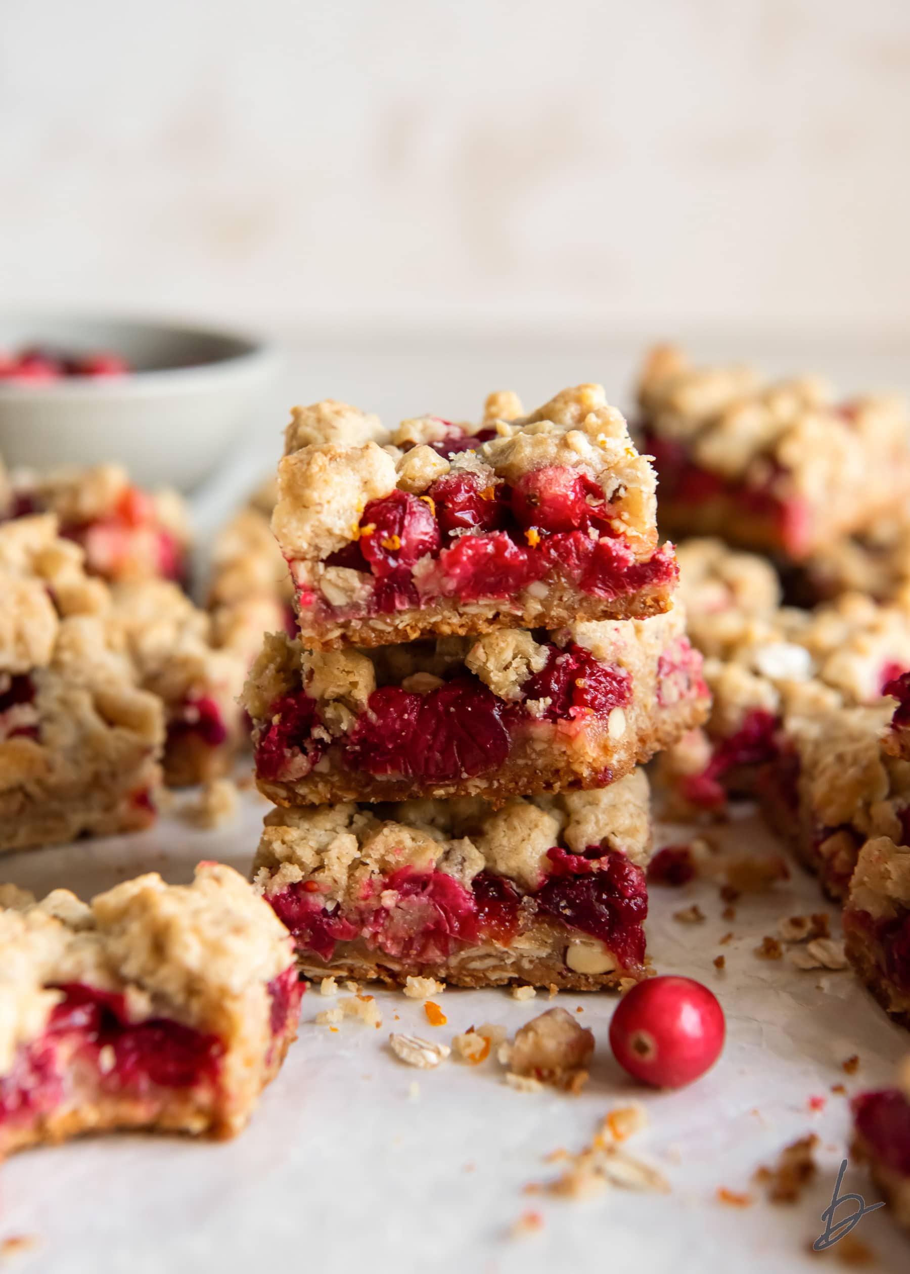 stack of three cranberry crumble bars surrounded by more bars.