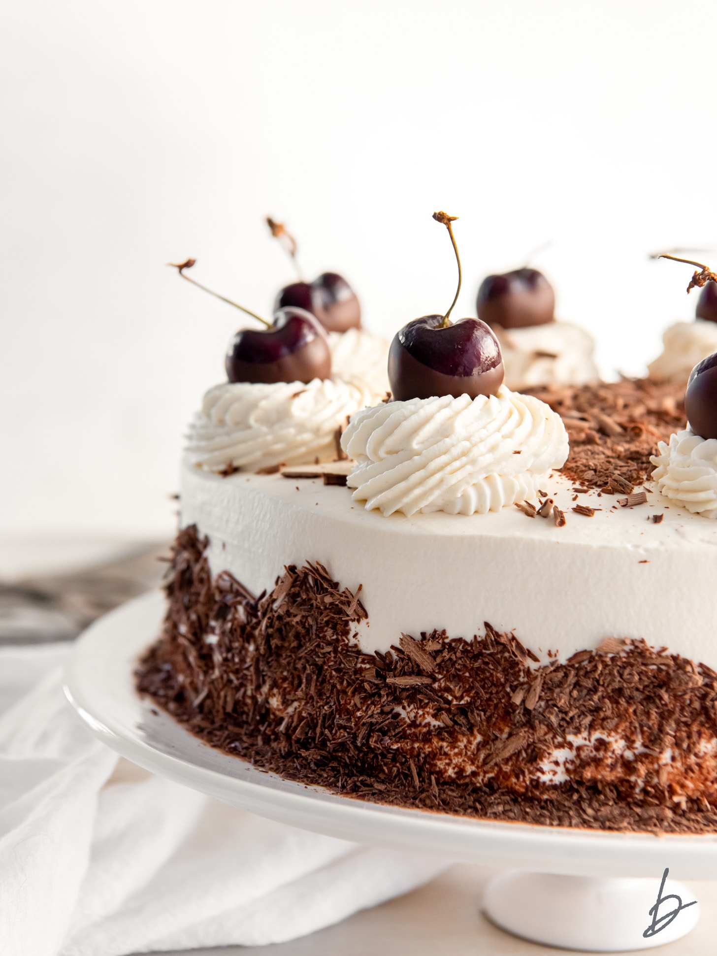 black forest cake garnished with chocolate shavings, whipped cream and cherries.