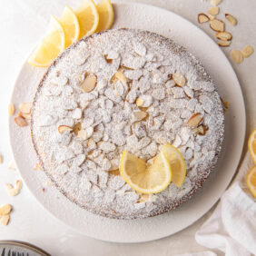 lemon ricotta cake with almonds, confectioners' sugar and lemon wedges as garnish.