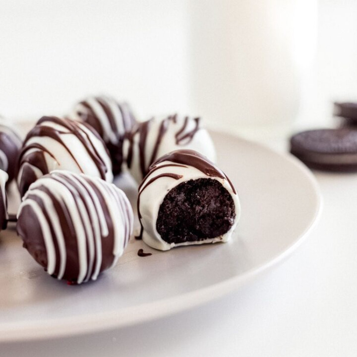 oreo truffle with a bite on plate with more oreo truffles.