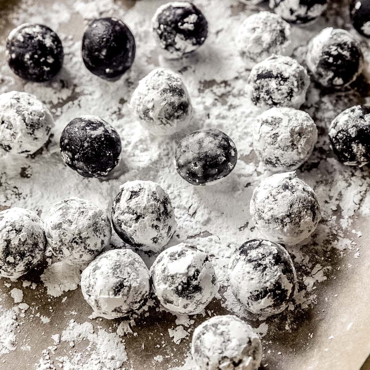 rum balls on baking sheet with parchment paper and confectioners' sugar.