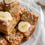 banana coffee cake squares in a pile with glaze and fresh banana slices.