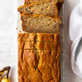 loaf of buttermilk banana bread with a couple slices cut off the end.