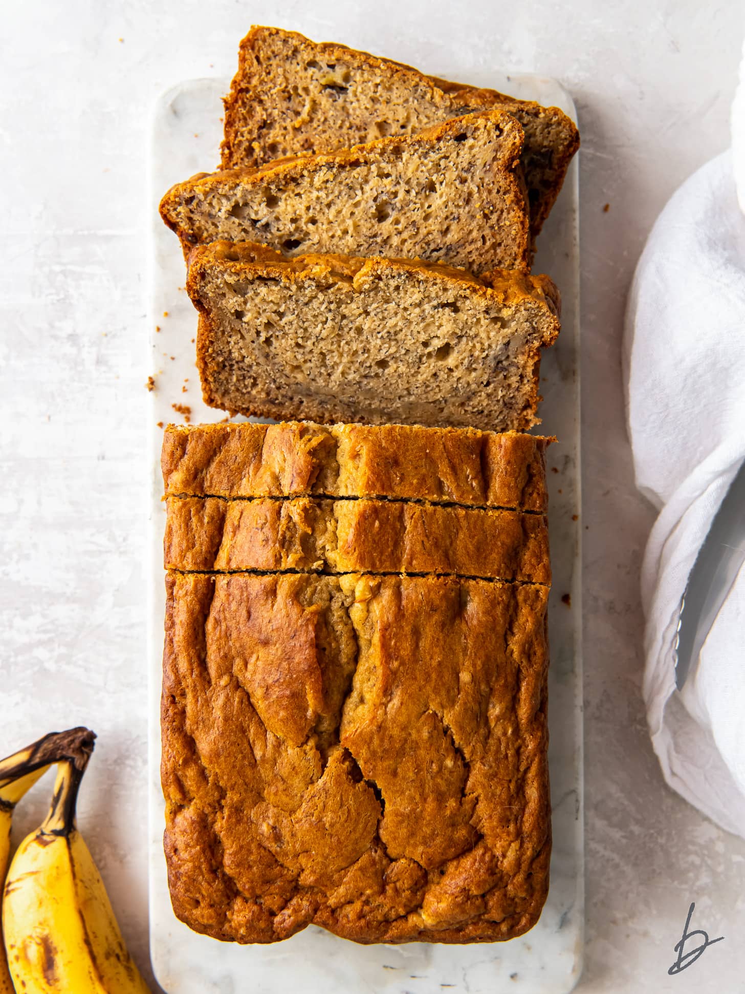 loaf of buttermilk banana bread with a couple slices cut off the end.