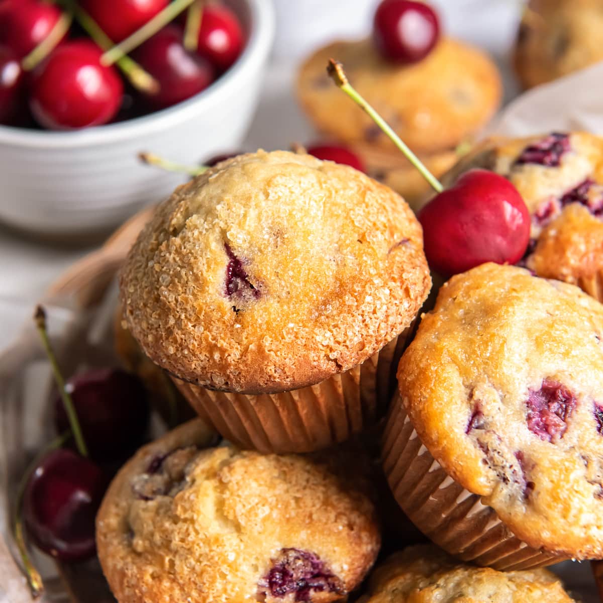 cherry muffins in a basket with a couple fresh cherries.