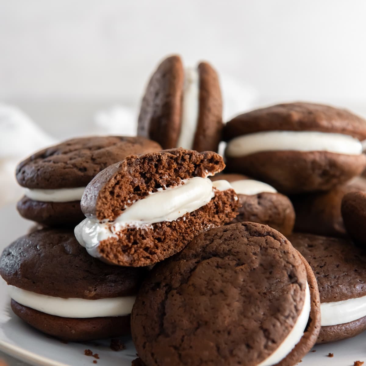 chocolate whoopie pie with cream cheese filling cut in half on top of more whoopie pies.
