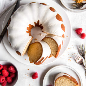 vanilla bundt cake with glaze and two slice cut next to one slice on plate.