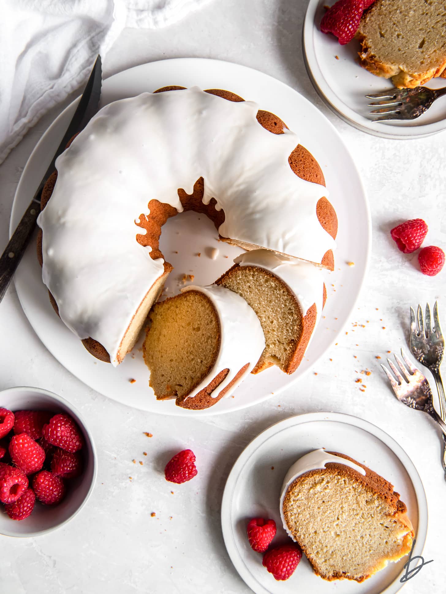 vanilla bundt cake with glaze and two slice cut next to one slice on plate.