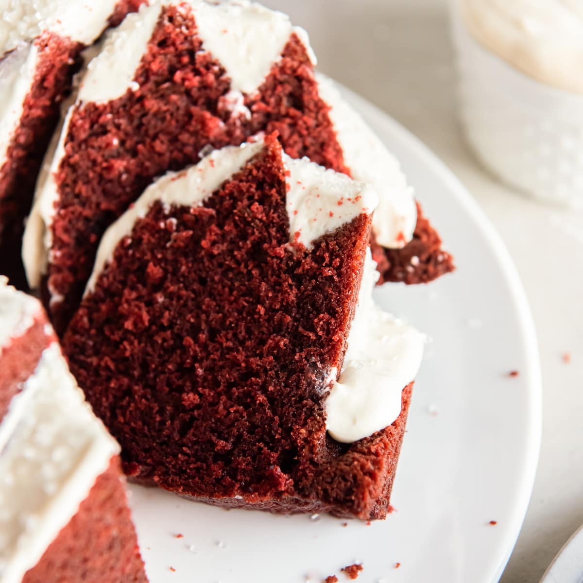 red velvet bundt cake slice leaning up against cake with cream cheese frosting.