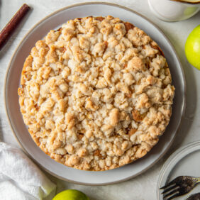 Irish apple cake with crumble topping on a plate next to Granny Smith apples.