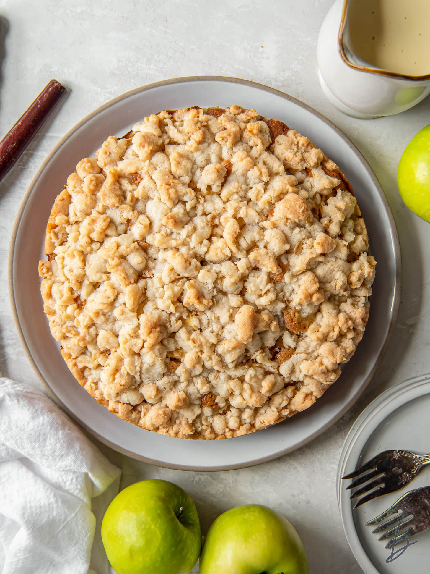 Irish apple cake with crumble topping on a plate next to Granny Smith apples.