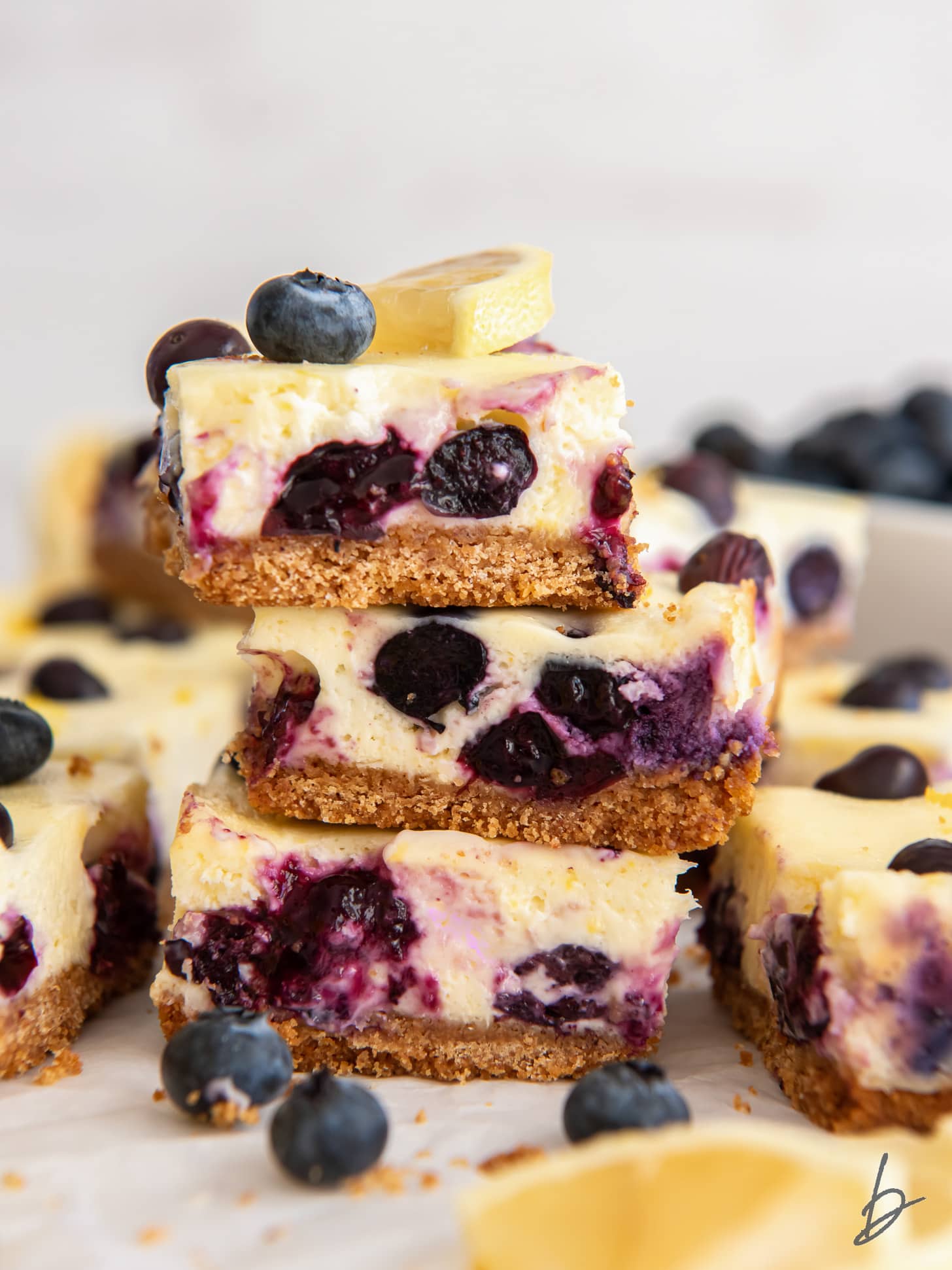 stack of three lemon blueberry cheesecake bars with graham cracker crust.