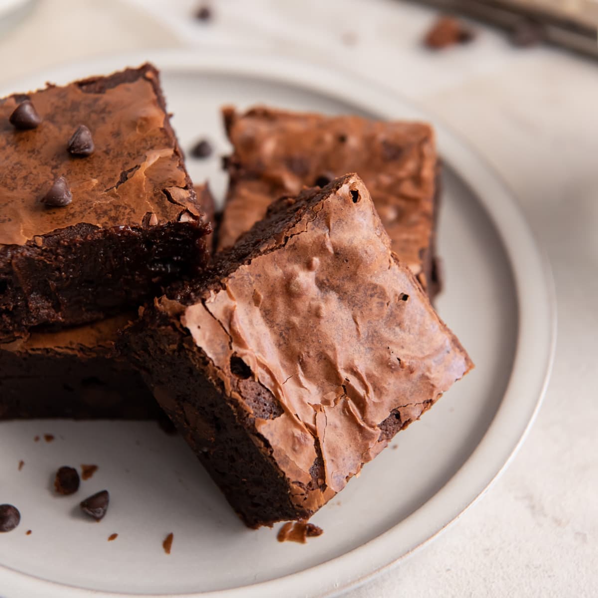 a few crinkly top fudgy brownies on a plate.