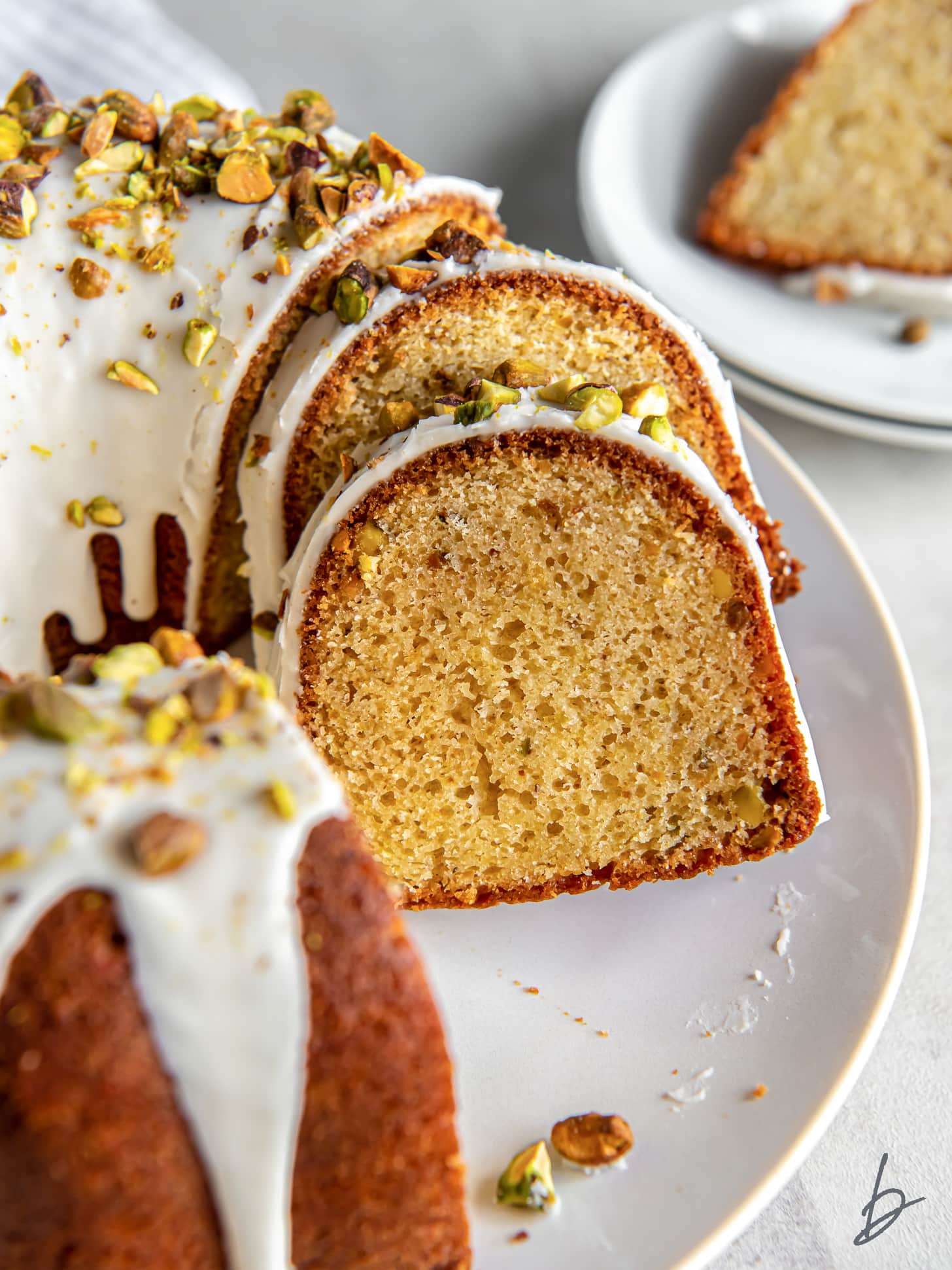 slices of pistachio bundt cake leaning against each other and cake on plate.
