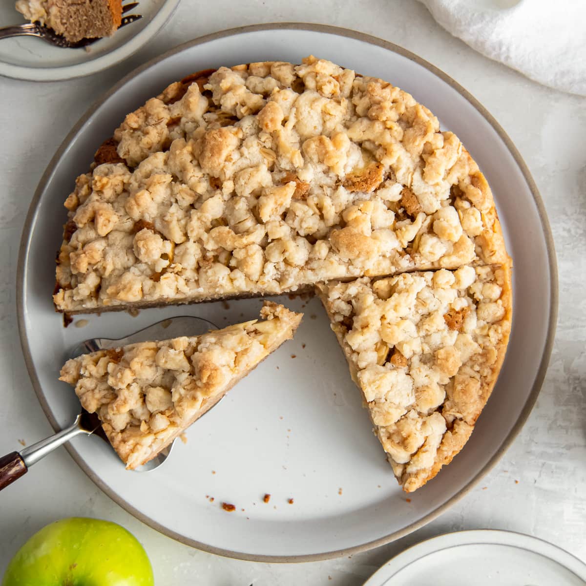 Irish apple cake with crumble topping on a plate with cake server holding a slice.