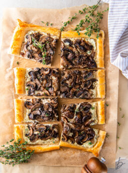 mushroom tart with goat cheese and puff pastry on parchment paper with thyme springs.