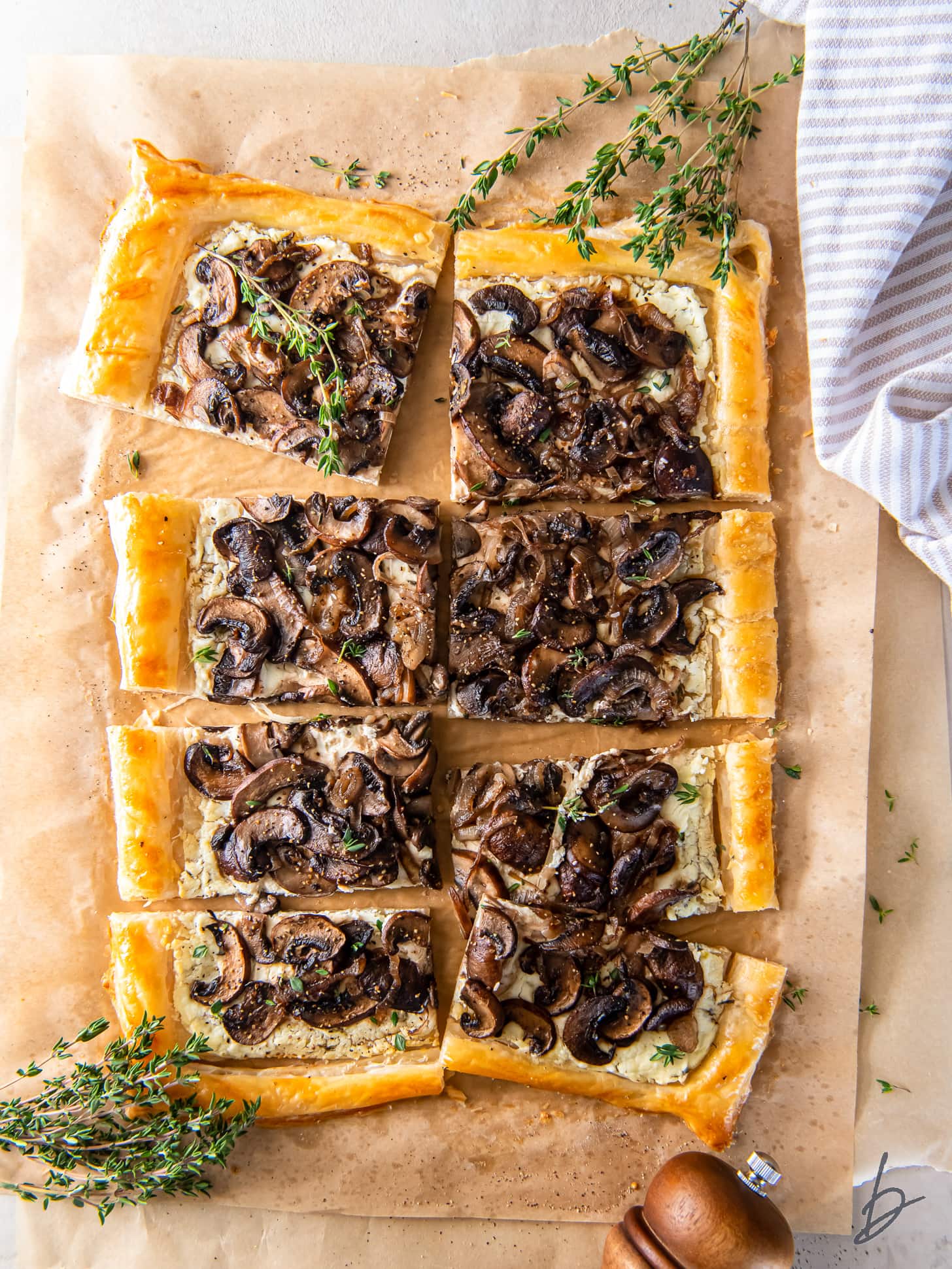 mushroom tart with goat cheese and puff pastry on parchment paper with thyme springs.