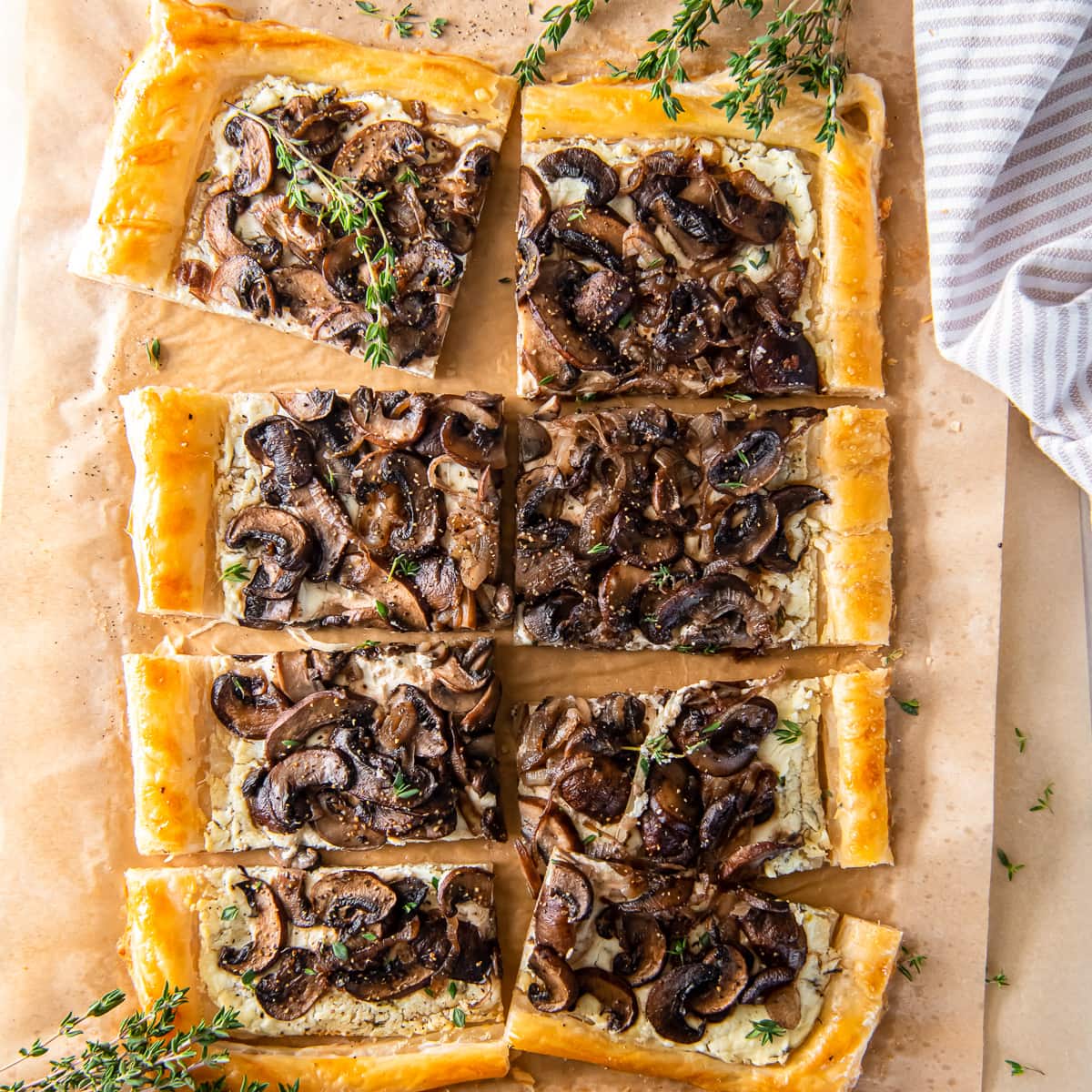 mushroom tart with puff pastry on parchment paper with thyme sprigs.