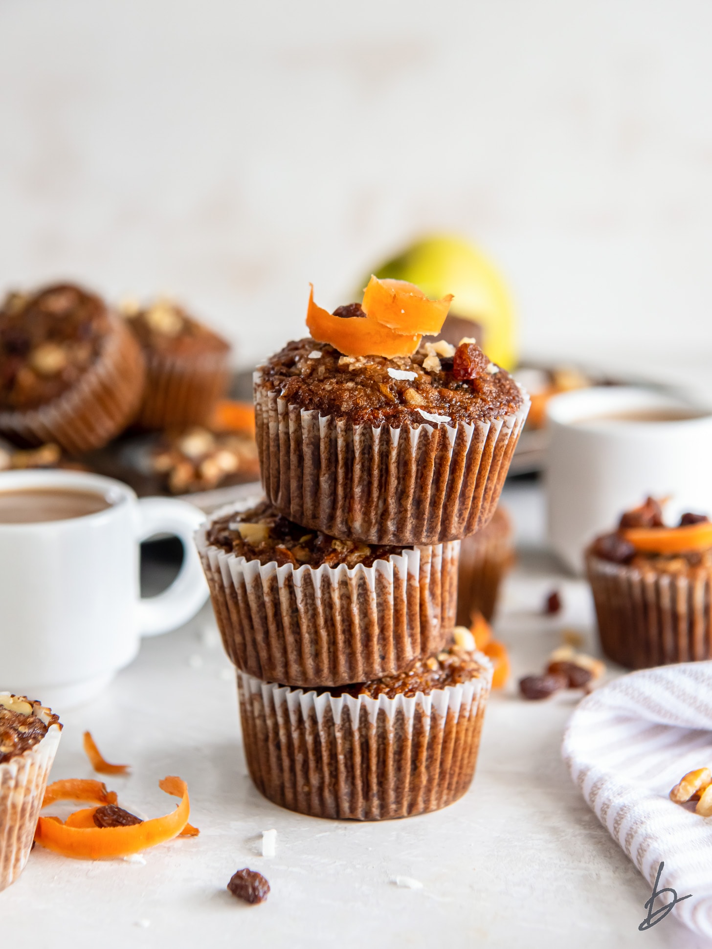 stack of three morning glory muffins with carrot shred on top.