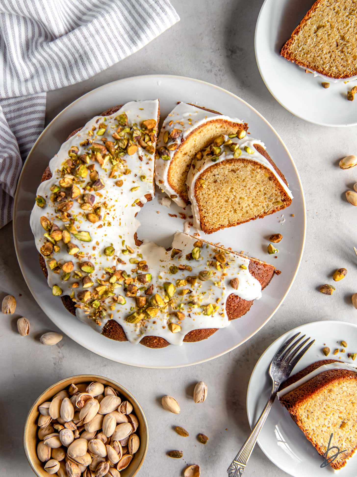 pistachio bundt cake on a plate with two slices cut off.