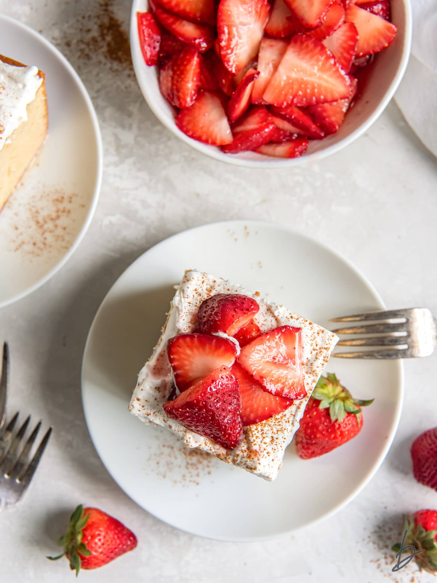 square sllce of tres leches cake with strawberries and whipped cream topping.