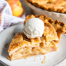 plate with slice of apple pie with a scoop of vanilla ice cream.