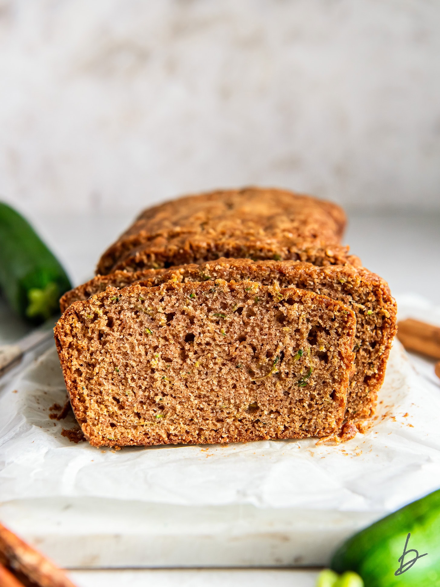 Moist cinnamon zucchini bread slice leaning on the loaf.