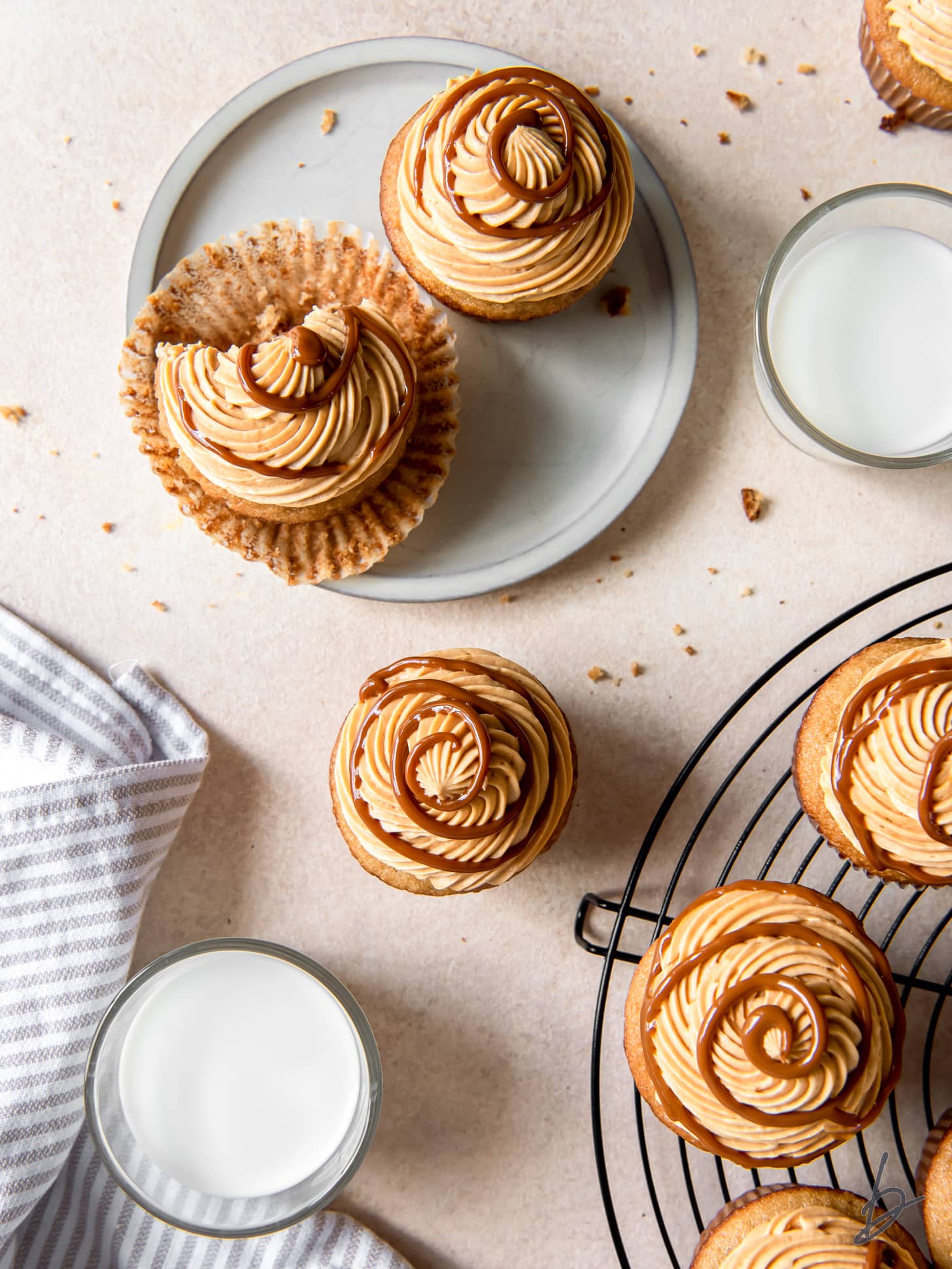 tops of dulce de leche cupcakes with frosting and swirl next to a glass of milk.